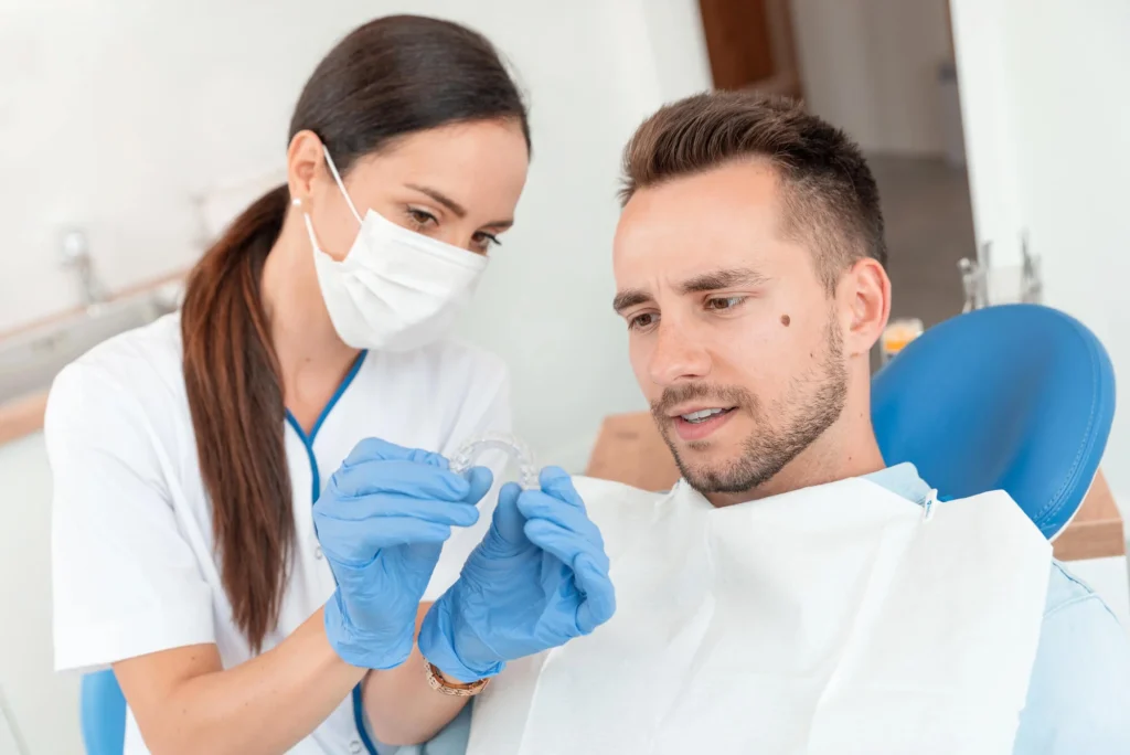 A dentist in Matthews, NC, and a male patient are talking about aligners