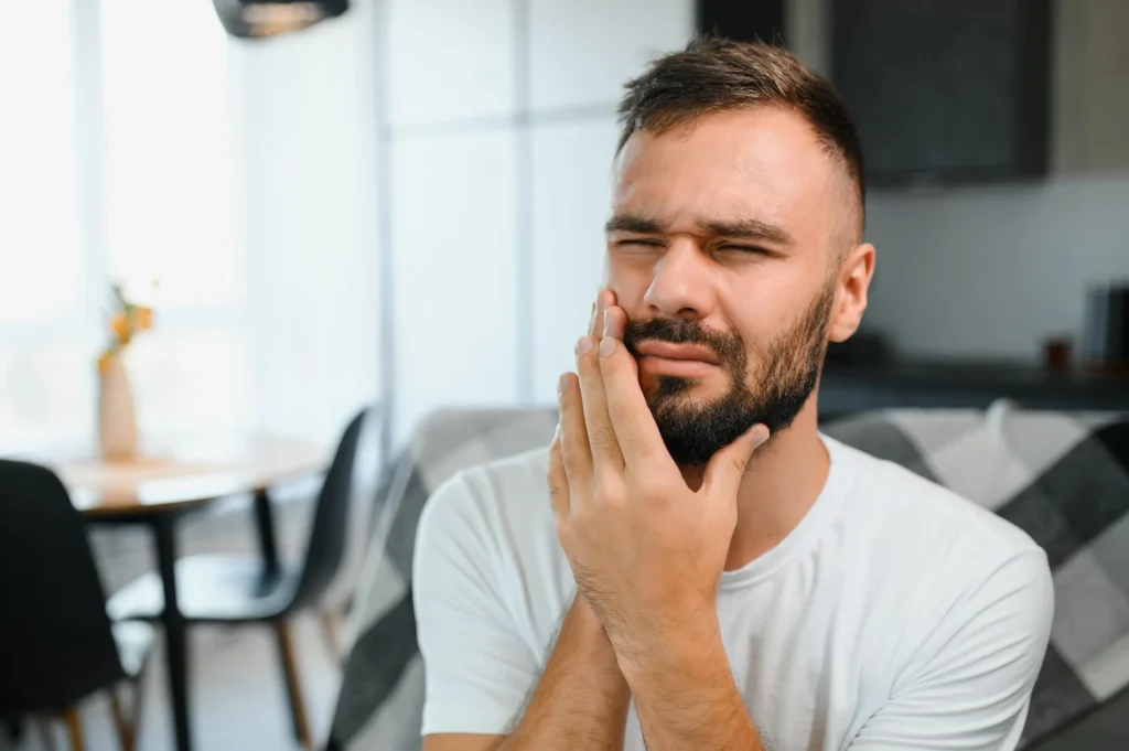 A young man suffering from toothache at home, in need of emergency dentist in Matthews, NC