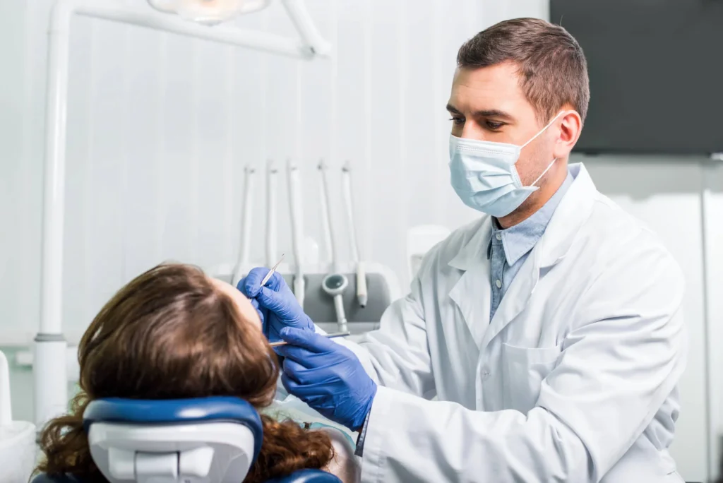 Emergency dentist in Matthews, NC, wearing a mask, working with latex-gloved hands